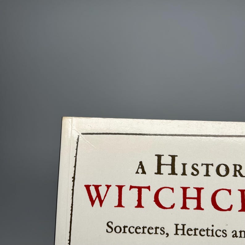 Op de afbeelding: Boekomslag met de titel "A History of Witchcraft" in zwarte en rode letters. De ondertitel luidt "Sorcerers, Heretics and Pagans". De omslag heeft een witte achtergrond met een zwarte rand.
