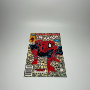 May include: A Marvel Comics Spider-Man comic book titled Torment Part One of Five. The cover features a red and blue costumed character crouching amidst a detailed web pattern against a light green background with the text 1st All-New Collector's Item Issue.