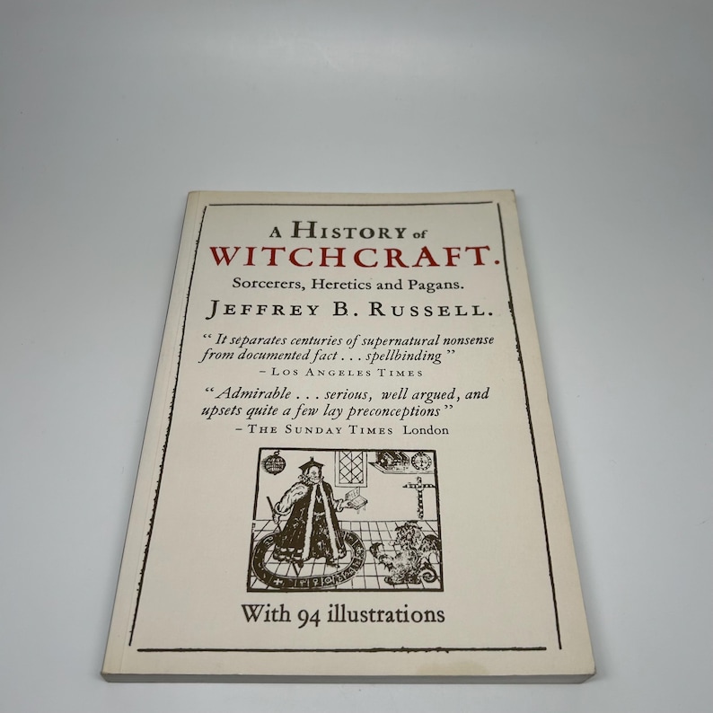 Op de afbeelding: Boek 'A History of Witchcraft' van Jeffrey B. Russell. De omslag is cr&egrave;mekleurig met zwarte tekst en illustraties. De titel van het boek, de auteur en citaten uit recensies worden weergegeven. Het boek bevat 94 illustraties.