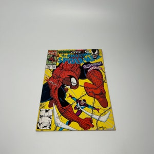 May include: A comic book cover featuring Spider-Man in a red and blue suit, fighting Venom. The cover is yellow with the text "Venom Lives! The Amazing Spider-Man" and "Boomerang".