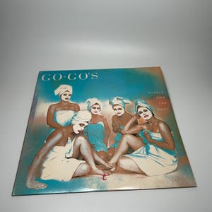 May include: Album cover for "Beauty and the Beat" by The Go-Go's. The album cover features five women wearing face masks and wrapped in towels. The album title and band name are visible on the cover.