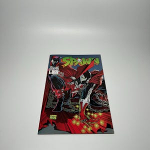 May include: Spawn comic book issue #8. The cover features a dynamic illustration of the Spawn character in a red cape, black and white suit, and chains. The title "SPAWN" is displayed in green and yellow. The Image Comics logo is visible.