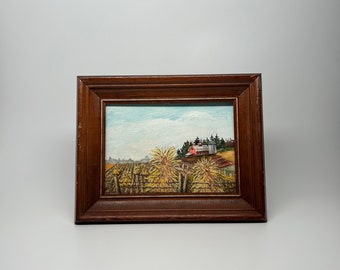 May include: A framed painting of a rural landscape with a red barn and a field of dried corn stalks. The painting is set against a blue sky with white clouds.