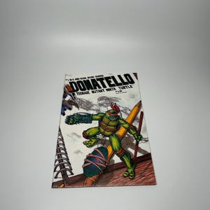 May include: A comic book cover featuring Donatello from Teenage Mutant Ninja Turtles. The cover art shows Donatello in a fighting stance, with a red mask, green skin, and a weapon. The title "DONATELLO" is prominently displayed.