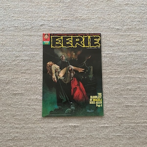 May include: A vintage comic book cover featuring a man in a black cloak carrying a woman in a white dress. The cover is for Eerie comic book number 46 and features the text "The Bloodlust of Dracula Rises Again Page 6".