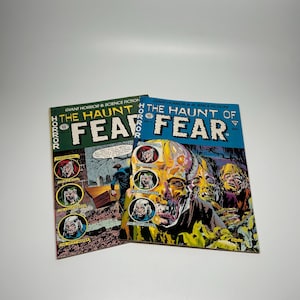 May include: Two vintage comic books titled "The Haunt of Fear" are displayed. One has a green cover, the other is blue. The covers feature horror-themed illustrations and the text "Giant Horror & Science Fiction".