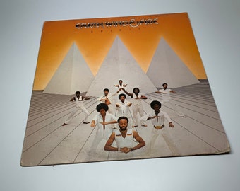 May include: A vintage vinyl record album cover featuring Earth, Wind & Fire. The album title "Spirit" is printed in white on a yellow background. The band members are dressed in white and are posed in front of a pyramid-shaped structure.
