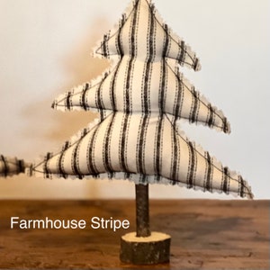 Pu&ograve; includere: Un piccolo albero di Natale in tessuto a strisce bianche e nere con una base in legno rustica. L'albero &egrave; decorato con un motivo a strisce in stile farmhouse.