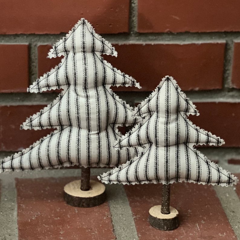 Pu&ograve; includere: Due alberi di Natale in tessuto a righe bianche e nere con una base in legno rustica.