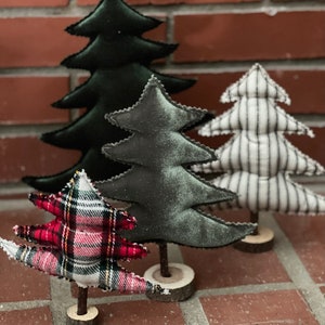 Pu&ograve; includere: Quattro alberi di Natale in miniatura realizzati in tessuto. Gli alberi sono decorati con quadri, strisce bianche e nere e un tessuto verde scuro. Gli alberi sono su basi di legno.