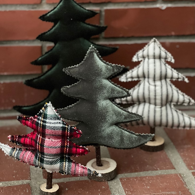 Pu&ograve; includere: Quattro alberi di Natale in miniatura realizzati in tessuto. Gli alberi sono decorati con quadri, strisce bianche e nere e un tessuto verde scuro. Gli alberi sono su basi di legno.