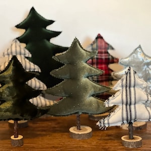 Pu&ograve; includere: Cinque alberi di Natale in miniatura realizzati in tessuto. Gli alberi sono decorati con diversi motivi, tra cui scozzese, strisce e velluto. Gli alberi sono in piedi su basi di legno.