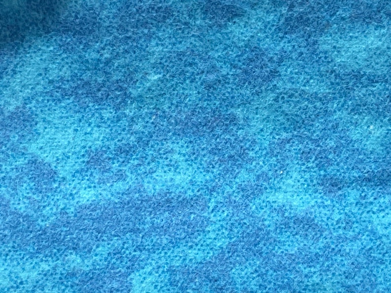 May include: A close-up of a blue textured fabric with a subtle mottled pattern.