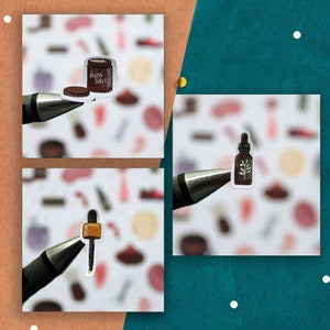 May include: Three stickers on white paper with a pen. The stickers are of a brown jar with the text "Bath Salts", a brown bottle with a green leaf, and a brown dropper with a gold top.