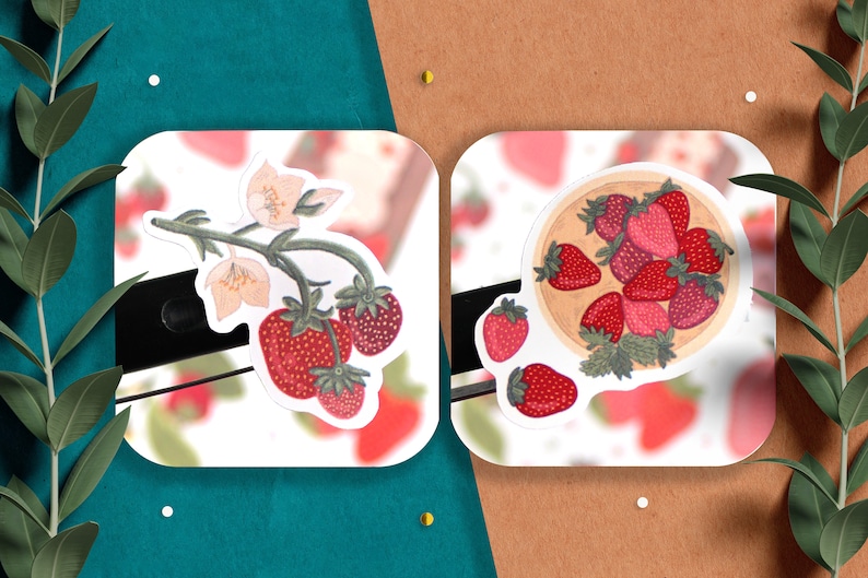 May include: Two stickers featuring illustrations of strawberries. The first sticker shows a strawberry plant with white flowers and red strawberries. The second sticker shows a bowl of red strawberries.