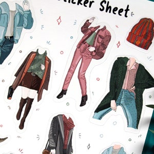 May include: A sticker sheet with illustrations of people wearing different outfits. The outfits include a blue jacket, a red jacket, a green cardigan, a brown coat, and a black coat. The sticker sheet also includes a red beanie.
