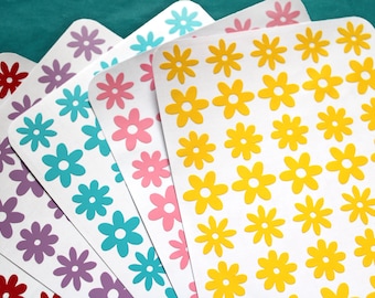 May include: Five sheets of white paper with a repeating pattern of yellow, pink, blue, purple, and red flowers. Each sheet has a different color flower.