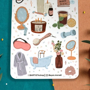 May include: A white sticker sheet with illustrations of various self-care items, including a bath tub, a bath brush, a sleep mask, a robe, a candle, a cup of tea, a dumbbell, a mirror, and a vase of flowers. The sticker sheet also includes the text "E:BARTISTA shop | @Bayan.moradi".