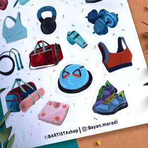 May include: A sheet of colorful stickers featuring various fitness and gym equipment, including dumbbells, a kettlebell, a yoga mat, a jump rope, a sports bra, a gym bag, and a balance ball. The stickers are on a white background with a light blue and pink pattern. The text "E:BARTISTAshop | @Bayan.moradi" is at the bottom of the sheet.