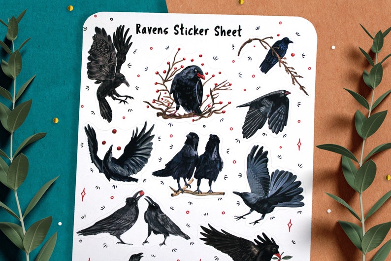 May include: A sticker sheet with a white background and nine black raven illustrations. The ravens are depicted in various poses, including flying, perched on branches, and looking at berries. The text "Ravens Sticker Sheet" is printed at the top of the sheet.