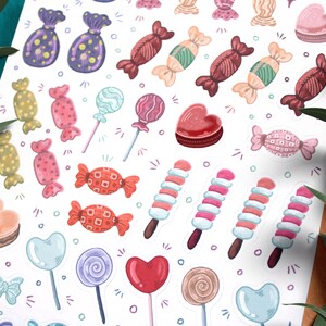 May include: A sheet of colorful candy stickers with various shapes and designs, including lollipops, hearts, and wrapped candies. The stickers are on a white background.