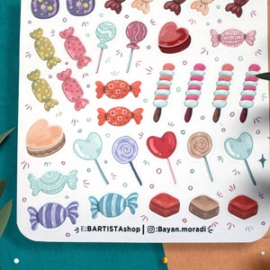 May include: A sheet of colorful stickers featuring various candy designs, including lollipops, hearts, and wrapped candies. The stickers are perfect for adding a touch of sweetness to planners, journals, and other craft projects.