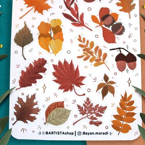 May include: A sheet of stickers featuring various autumn leaves in shades of brown, orange, and red. The stickers are arranged in a random pattern on a white background. The text "E:BARTISTAshop | @Bayan.moradi" is printed at the bottom of the sheet.