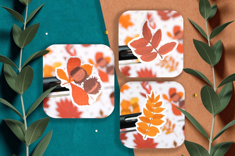 May include: Three autumn-themed stickers featuring different leaf designs. The first sticker shows a red and orange leaf with three brown chestnuts. The second sticker shows a red leaf with a stem and multiple branches. The third sticker shows an orange leaf with a stem and multiple branches.