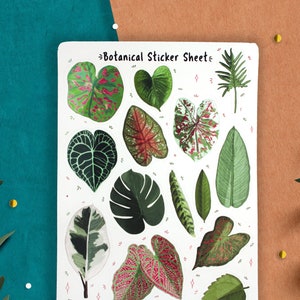 May include: A sheet of botanical stickers featuring various green, white, and pink leaves. The sticker sheet has the text "Botanical Sticker Sheet" at the top.