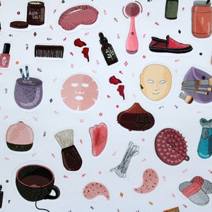 May include: A sheet of stickers featuring various beauty and self-care items, including a face mask, bath salts, a facial cleansing brush, a jade roller, a makeup brush, and a cup of tea. The stickers are on a white background with pink and purple accents.
