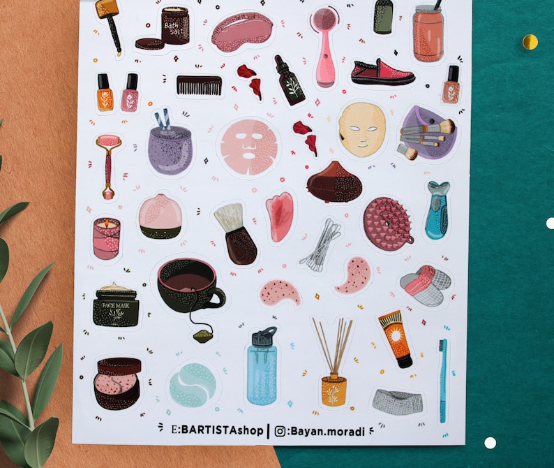 May include: A sheet of stickers featuring various beauty and self-care items, including a face mask, bath salts, a facial roller, a teacup, a bath bomb, a face scrub, and a bottle of essential oil. The stickers are on a white background with a light brown border.