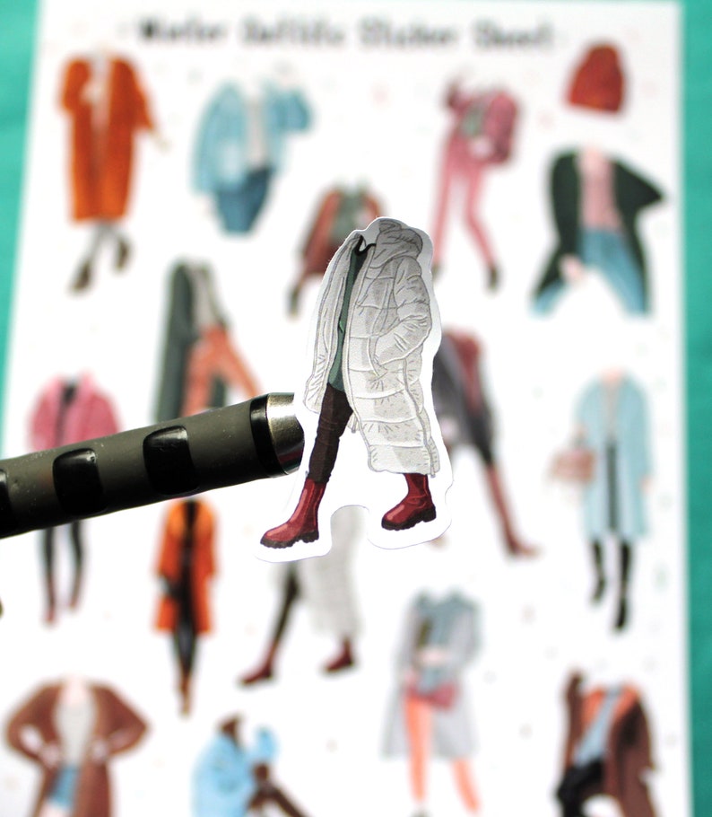 May include: A white puffer jacket with a black trim and red boots. The jacket is part of a set of paper doll stickers.