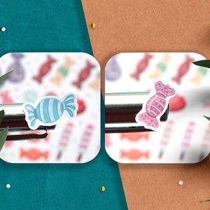 May include: Two candy stickers on a white background. The sticker on the left is blue and white with a swirl pattern. The sticker on the right is pink and white with a polka dot pattern.