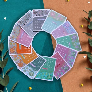 Peut inclure: Un ensemble de douze cartes de calendrier illustr&eacute;es, dispos&eacute;es en cercle. Chaque carte repr&eacute;sente un mois avec un design unique sur le th&egrave;me de la nature, avec des arbres et des feuilles. La palette de couleurs comprend des nuances de vert, d'orange et de violet.
