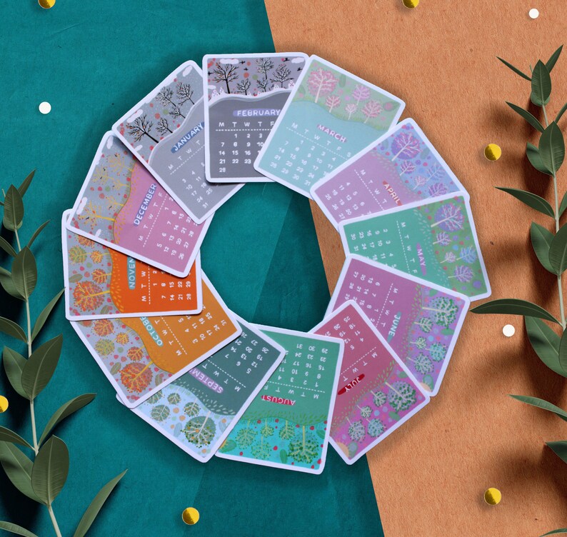 Peut inclure: Un ensemble de douze cartes de calendrier illustr&eacute;es, dispos&eacute;es en cercle. Chaque carte repr&eacute;sente un mois avec un design unique sur le th&egrave;me de la nature, avec des arbres et des feuilles. La palette de couleurs comprend des nuances de vert, d'orange et de violet.