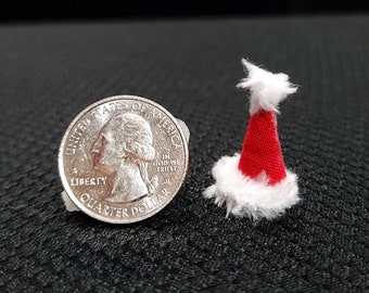 May include: A small red and white Santa hat with a white fur trim. The hat is about the size of a US quarter.