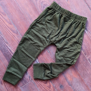 May include: A pair of dark green, casual pants with a drawstring waist and a relaxed fit.