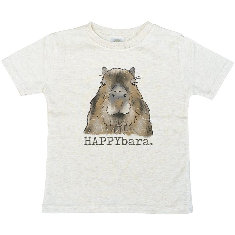 May include: A light gray t-shirt featuring a watercolor illustration of a capybara. The capybara is brown and tan with a detailed face. Below the image is the text "HAPPYbara."