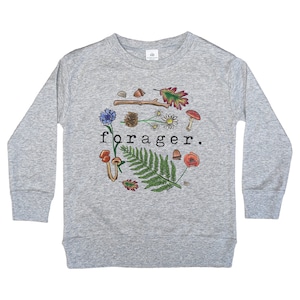 May include: A gray long-sleeved sweatshirt with a graphic design of a fern, mushrooms, flowers, and a branch. The text "forager." is printed in black on the front of the sweatshirt.