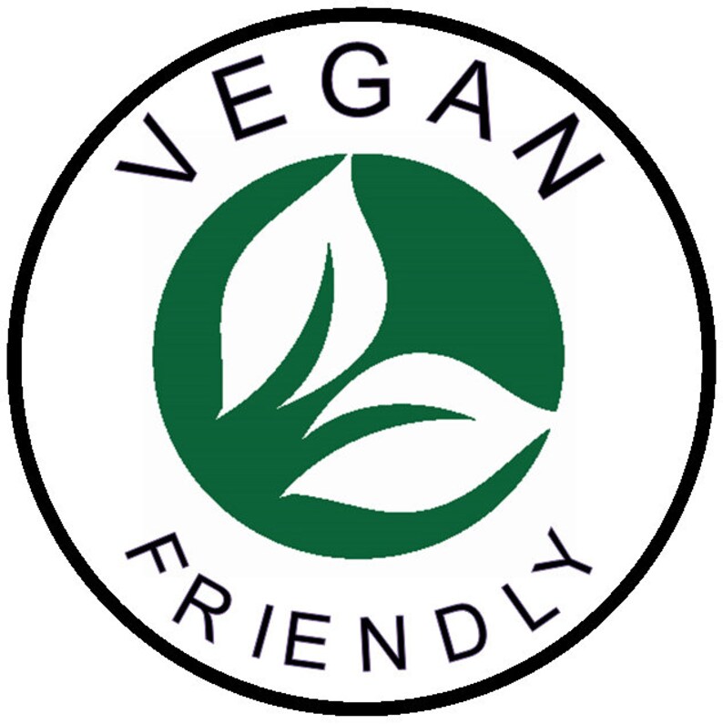 May include: A white circle with a black border and the text "VEGAN FRIENDLY" around the edge. Inside the circle is a green circle with three white leaves.