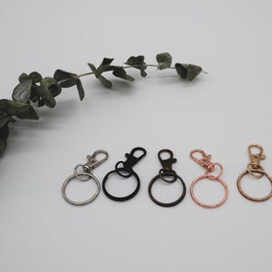 Puede incluir: Cinco llaveros con anillos y clips de metal de diferentes colores. Los llaveros son plateados, negros, dorados, oro rosa y cobre.