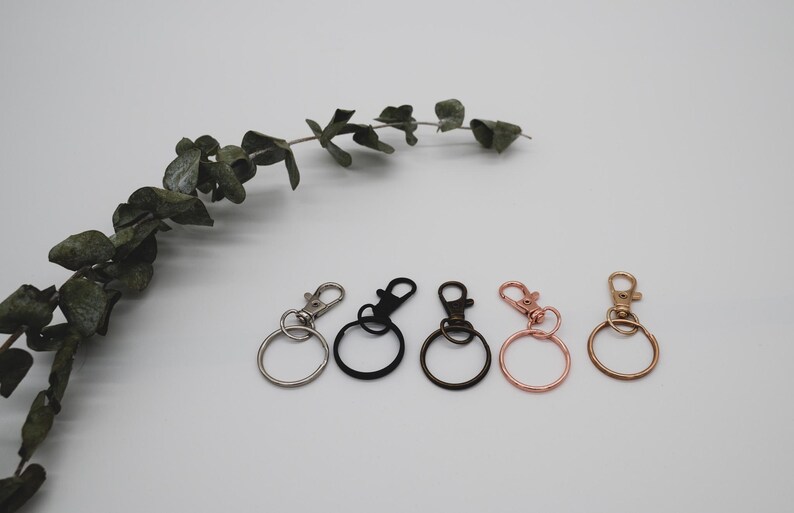 Puede incluir: Cinco llaveros con anillos y clips de metal de diferentes colores. Los llaveros son plateados, negros, dorados, oro rosa y cobre.