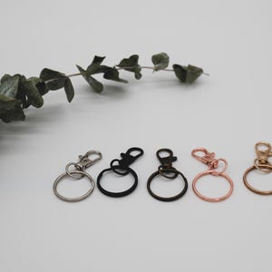 Puede incluir: Cinco llaveros con diferentes acabados met&aacute;licos. Los llaveros son plateados, negros, plateados, oro rosa y dorados.