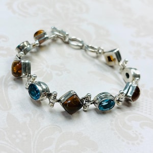 May include: A silver bracelet with alternating blue and brown gemstones. The bracelet has a lobster claw clasp.