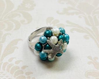 May include: A silver ring with a cluster of blue and white pearls and a silver starfish charm.
