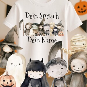 Op de afbeelding: Wit T-shirt met een Halloween-thema. Het ontwerp toont cartoonfiguren verkleed als geesten, heksen en mummies. De Duitse tekst "Dein Spruch Dein Name" staat boven en onder de figuren. Een grote zwarte spin hangt boven het shirt.