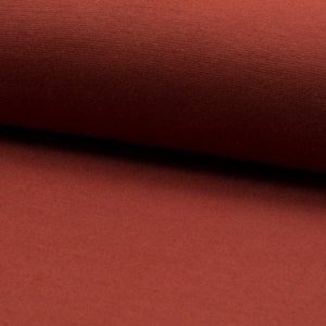 May include: Close-up of a rust-colored fabric with a textured surface. The fabric is soft and has a subtle sheen.