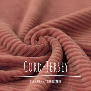 Op de afbeelding: Close-up van een werveling van kleiroze corduroy jersey stof. De stof heeft een geribbelde textuur en de woorden "CORD-JERSEY" staan bovenaan. Onder de tekst staan de woorden "CLAY PINK // ZIEGELSTEIN".