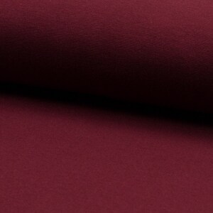 May include: Close-up of a deep burgundy fabric with a smooth, slightly textured surface.