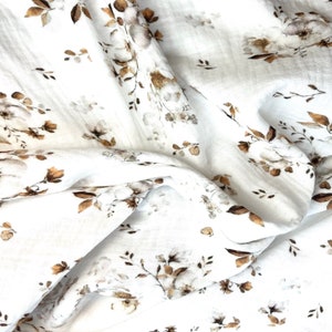 Puede incluir: Tela de muselina blanca con un estampado floral marr&oacute;n. La tela es suave y ligera, lo que la hace ideal para envolver, mantas u otros proyectos de artesan&iacute;a.